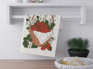 Illustrated strawberry basket tea towel design featuring red strawberries, white flowers, green leaves, and a woven basket in a cozy cottage garden style.