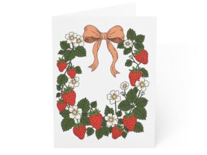 Greeting card design featuring strawberry wreath artwork with red berries, white flowers, green leaves, and a soft bow in a cottage garden style.